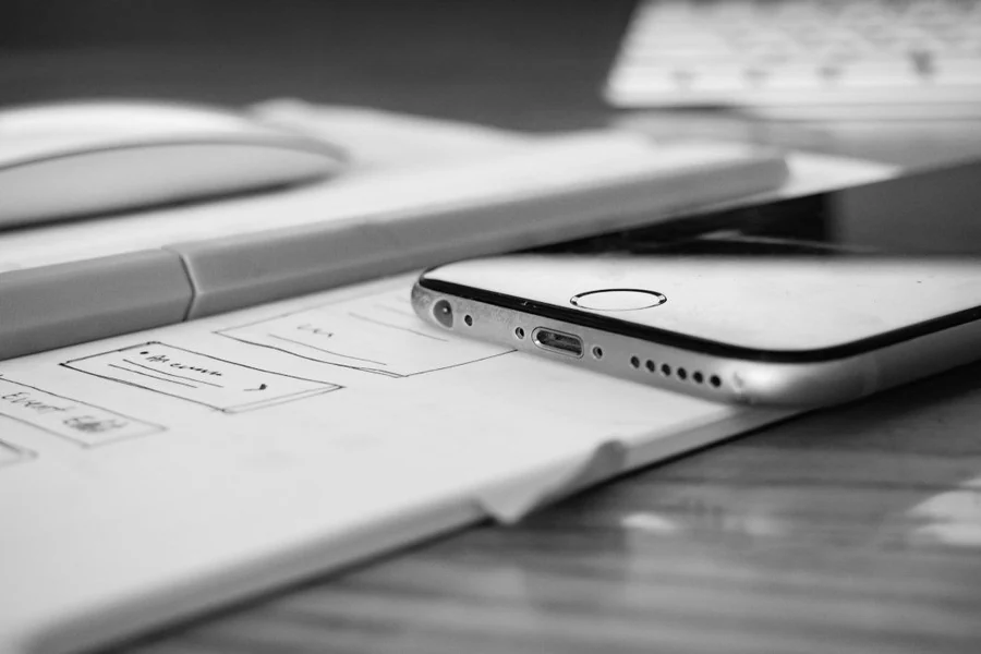 Black-and-white stock photograph of a smartphone resting on hand-drawn interface wireframes.