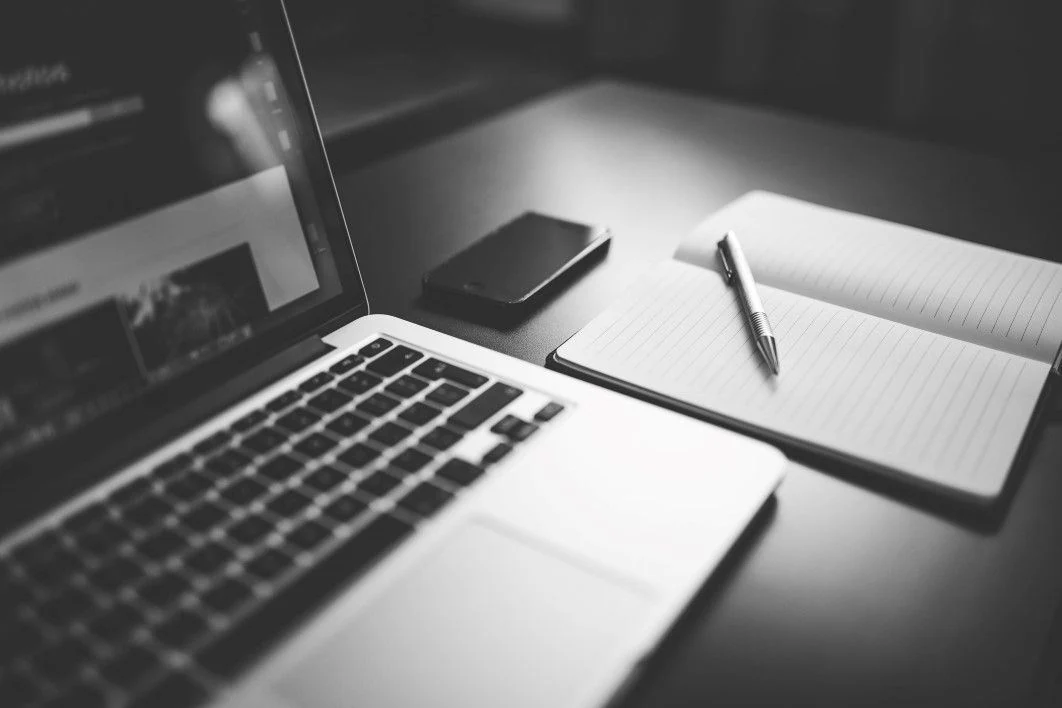 Stock photograph of a laptop, smartphone and notebook on a desk.